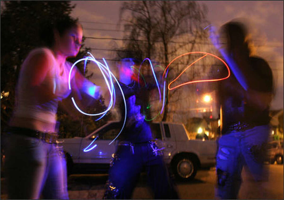 Near the scene of the Capitol Hill shootings, Giggles, 16, left, and Nemesis, 19, center, do a light show on the street as a tribute to "Sushi," their friend who was killed on Saturday.