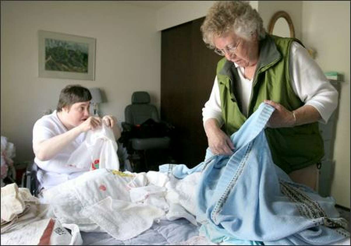 Janet Taggart, right, and her daughter Naida fold clothes in their home in Seattle after Naida returns home from her day school program Monday.