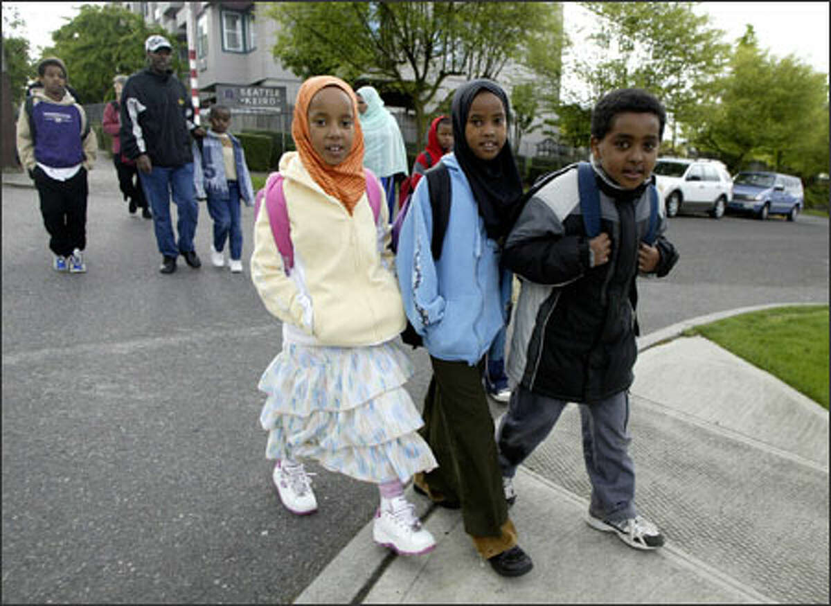 From left, Gabbiftu Aliye, 7, Asanti Umar, 8, and Tumuuda Tamaami, 8, walk to Bailey Gatzert Elementary on Monday under the "Walking School Bus" program.