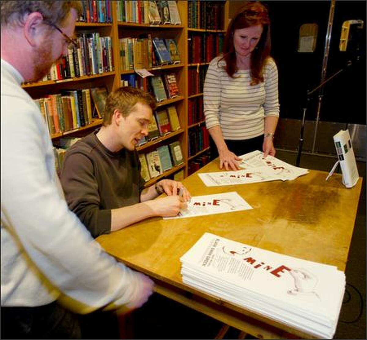 "Black Swan Green" author David Mitchell signs broadsides at Third Place Books April 26. With him are store managing partner Robert Sindelar, left, who had the idea for the broadsides, and Gail DiRe, the author's escort.