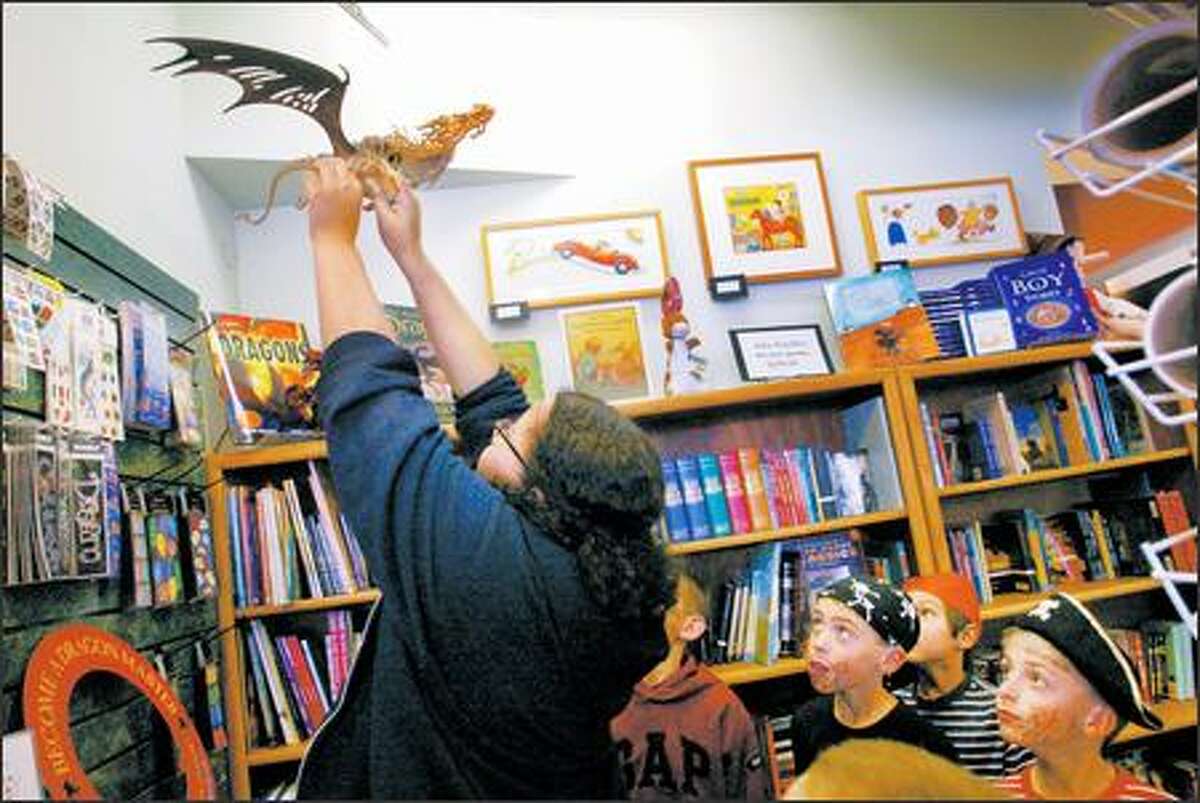 During a treasure hunt at All for Kids Books & Music, Julia Reed helps dislodge a clue from a hanging fake reptile skeleton. Kids from left: Justin Glazer, 8, Daniel Mah, 8, and Matt Glazer, 8.