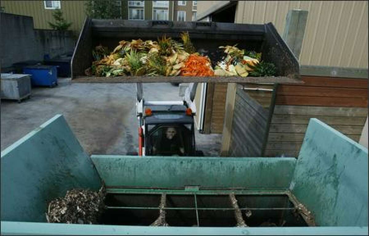Tyler Dierks of Seattle University dumps fruit and vegetable remains into a machine that mixes them with wood chips to form compost.
