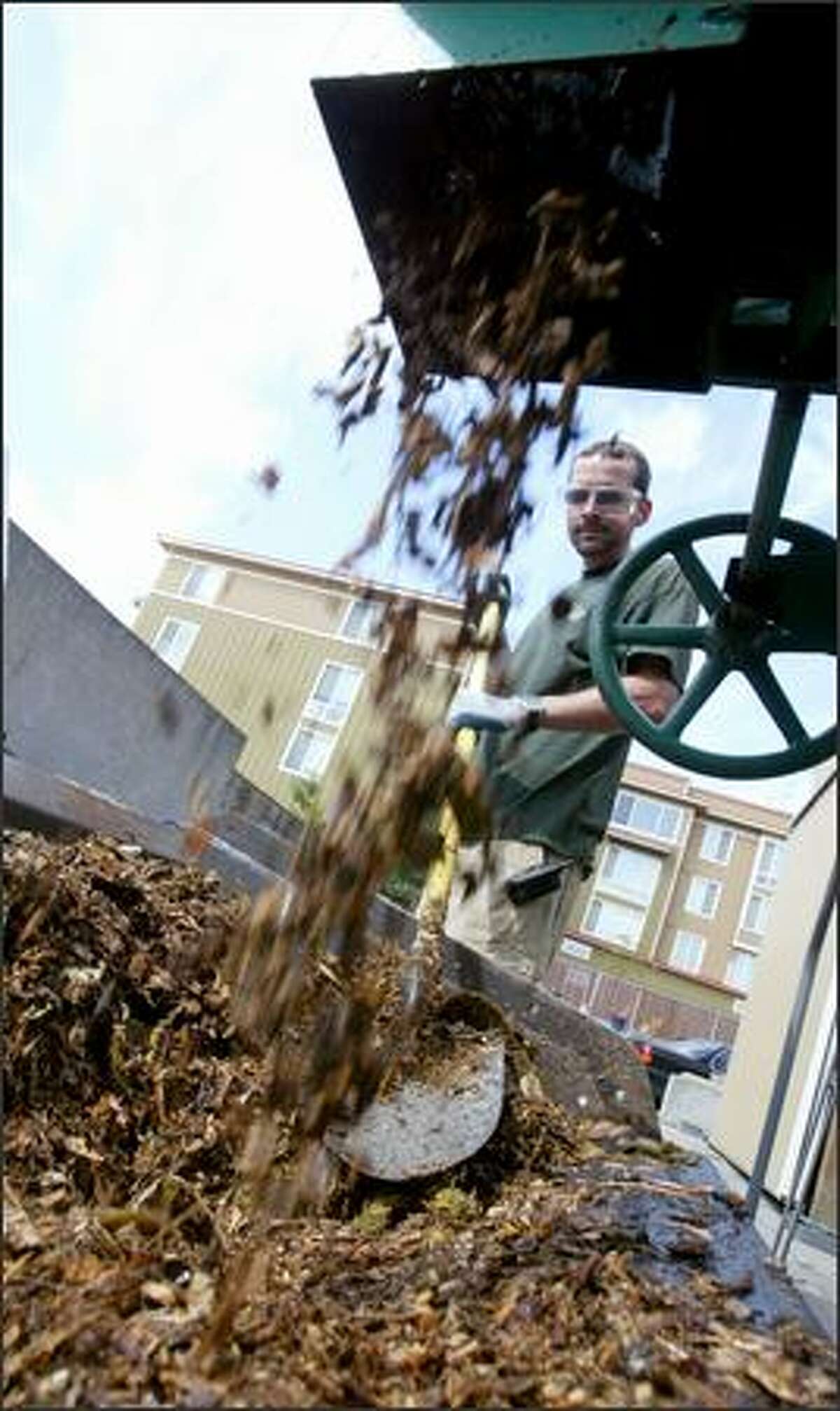 Dierks empties a composted mixture into a front-end loader before using it to fertilize. The school composts leftover produce, breads and coffee grounds.