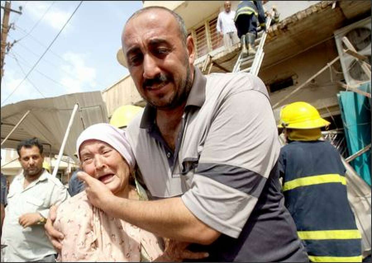 A man comforts an elderly woman after a roadside bomb ripped through an apartment building, killing four and wounding 14 in Baghdad's downtown Al-Nasir Square on Monday.