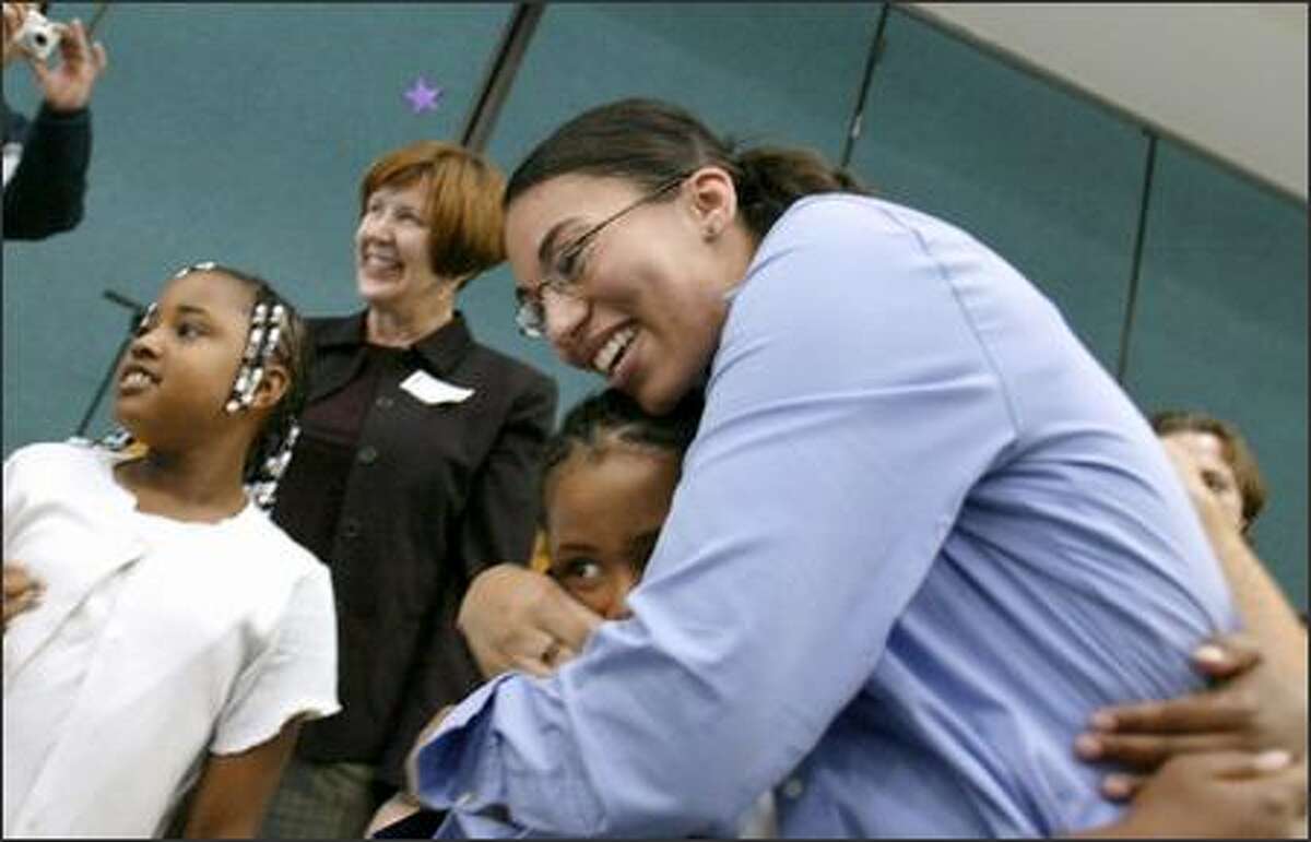 Thurgood Marshall Elementary teacher Cassandra Baddeley hugs student Faye Long, 10, after winning the Milken prize Wednesday. Octavia Grimes, left, and 1995 Milken winner Carol Coe, center, look on.