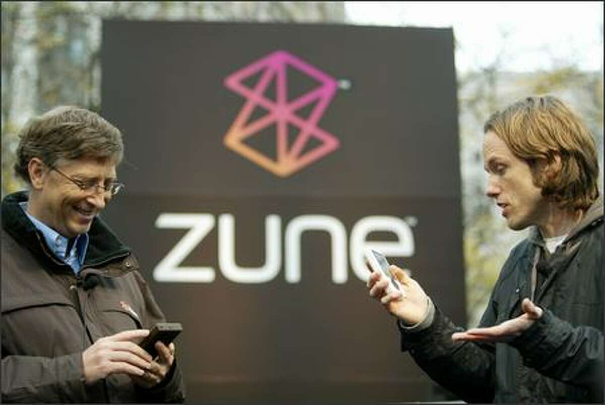 John Richards of Seattle radio station KEXP sends a song from his Zune to one held by Microsoft chairman Bill Gates by using the wireless sharing feature in the new music device at Westlake Park in Seattle on Monday.
