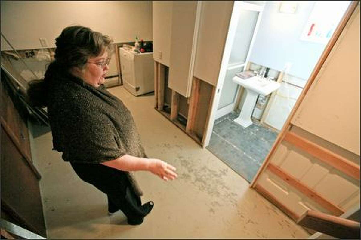 Jennifer Forrey points out flood damage to the newly renovated basement of the home she shares with Jack Lawless. Four feet of water filled the West Seattle basement during the rainstorm on Dec. 14. They plan to pursue claims against the city.