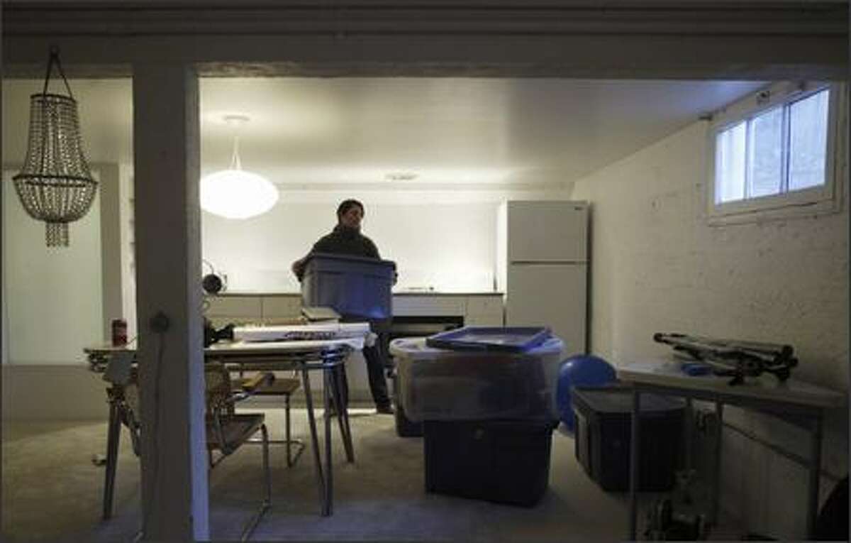 Randilyn Kealey moves around boxes in the basement of the house she and her fiancé, Mike Kimelberg, recently bought in Montlake. The couple plan to make the basement their master bedroom suite.
