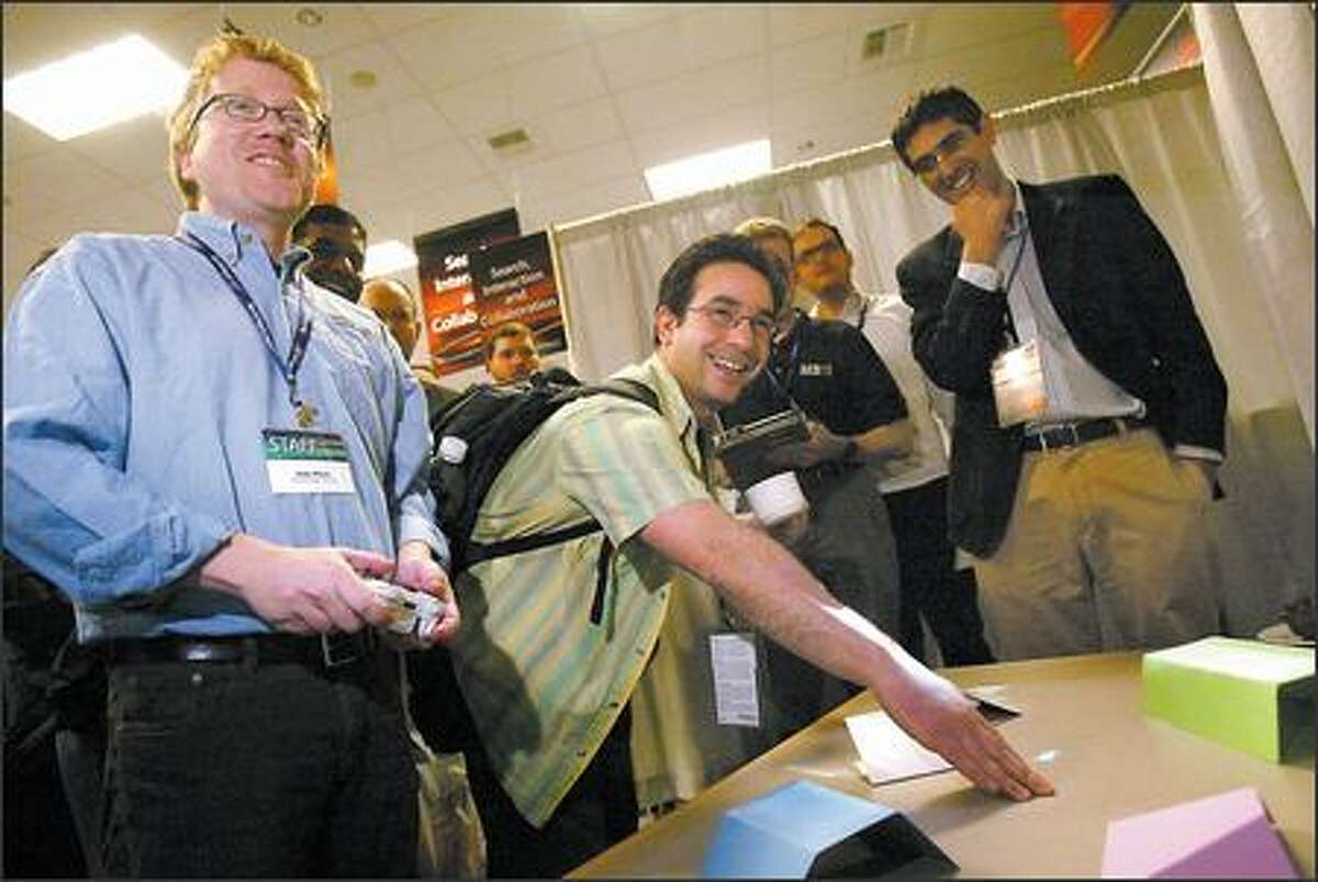 Andy Wilson, left, shows Alex Dimakis a prototype that lets people drive a tiny image of a car across and over real objects on a table at TechFest.