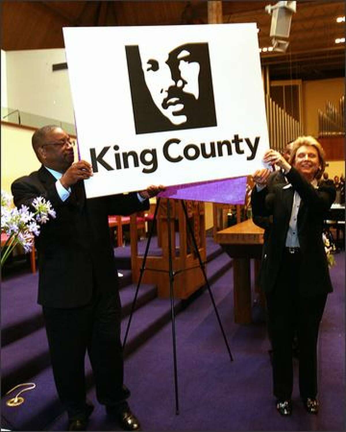 King County Council Chairman Larry Gossett and Gov. Chris Gregoire show the county's proposed logo of the Rev. Martin Luther King Jr. outside Mount Zion Baptist Church in Seattle on Sunday.