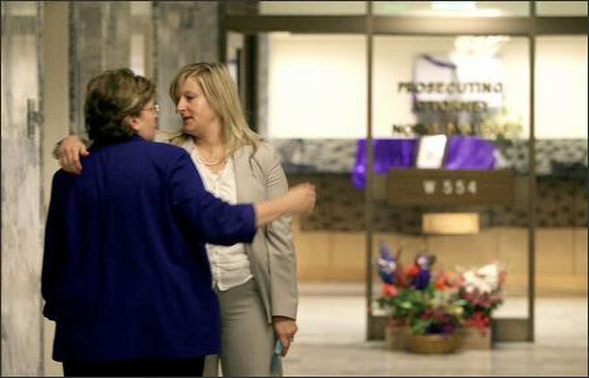 Maureen Galloway, left, legal services manager, and Cheryl Snow, senior deputy prosecutor, console each other at the courthouse Friday.