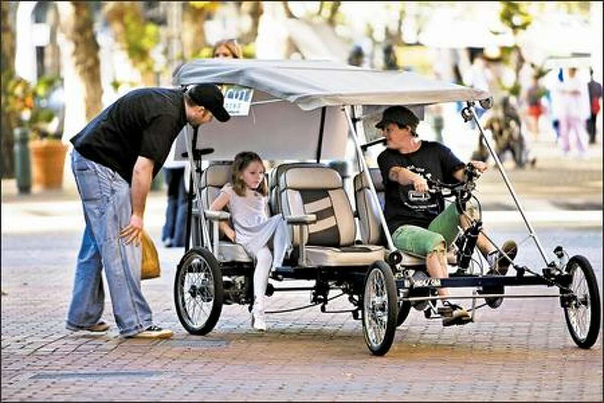 Candi Wilvang talks to Mitch Brausky and his daughter, Jocelyn, 5, as they board her four-wheel pedicab in Pioneer Square for a ride to Qwest Field.