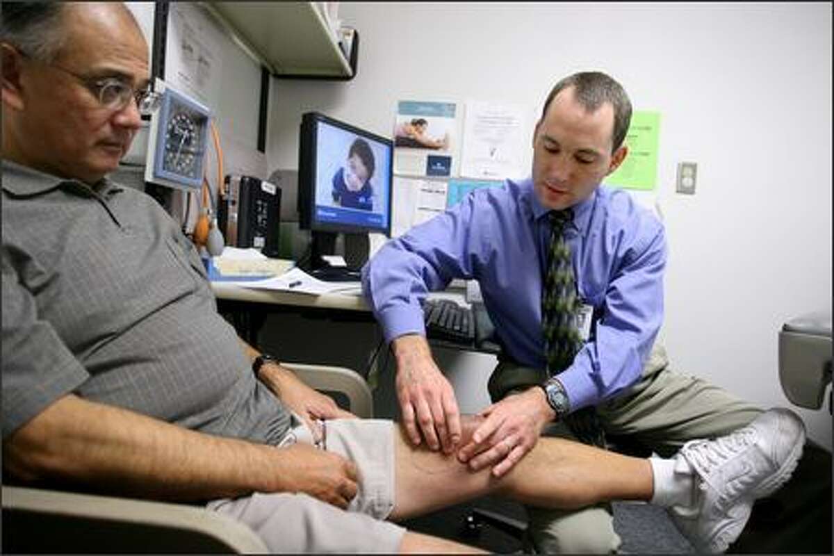 Dr. Eric Seaver examines Russell Akiyama's knee Tuesday. Seaver, a Group Health physician, regularly e-mails his patients. "I can provide better care to patients ... because I can now communicate with them on a weekly basis and make adjustments faster than I could if I was seeing these patients every three months in my office."