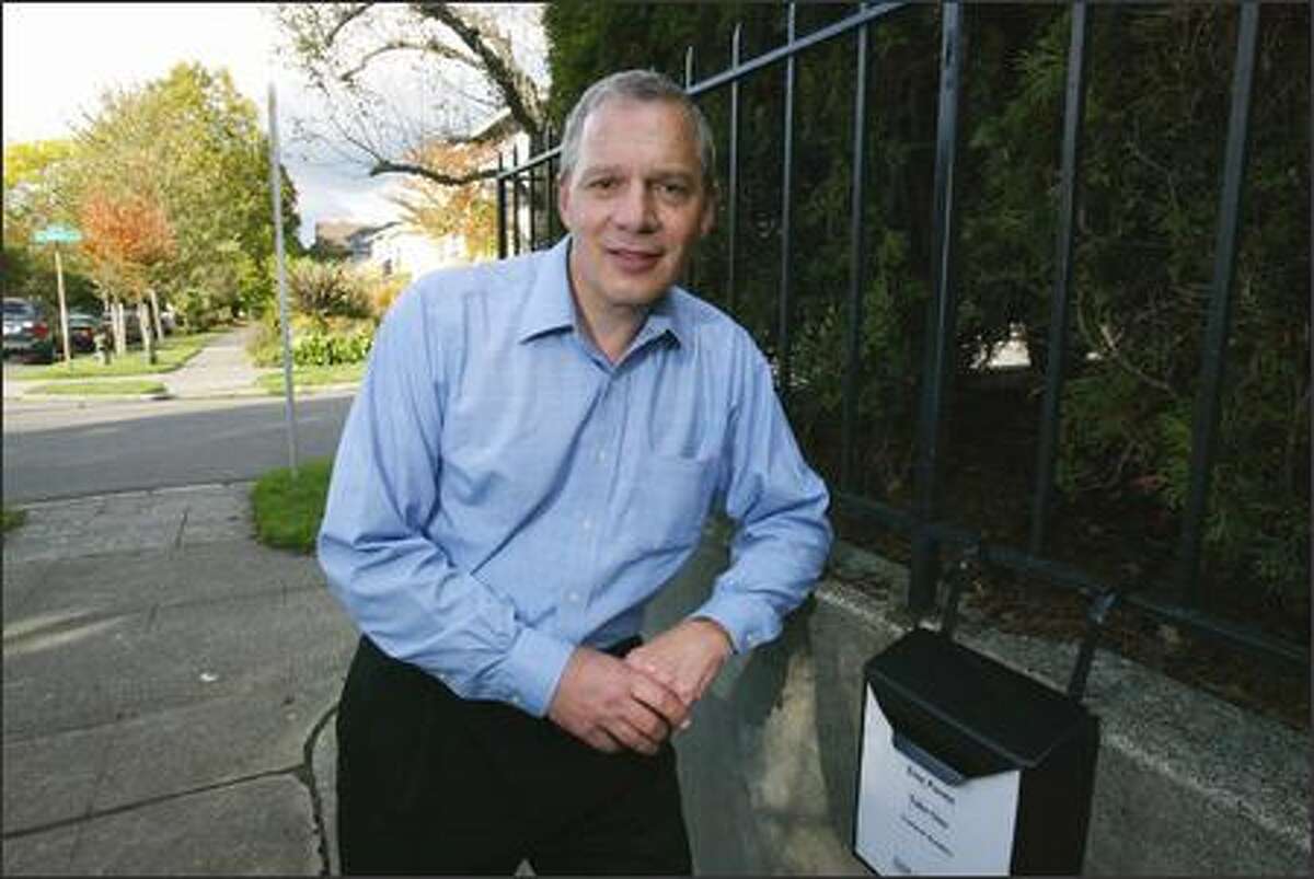 Guy Holliday poses next to a mailbox outside his Capitol Hill home last week. The box contains copies of his original poems for people walking by to pick up and read.