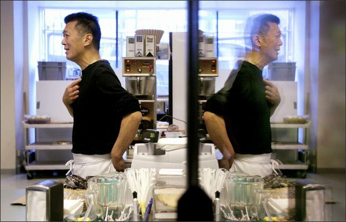 Jason Wang is reflected in a soft-drink cooler as he jokes with a customer Wednesday while manning the register at Bakeman's Restaurant in downtown Seattle.
