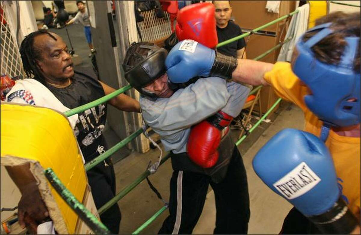Willi Briscoeray, left, supervises boxers Jumanne Moore, center, and Zsolt Dornay, right, as they spar at Bumblebee Boxing Club in Seattle. The boxers are governed by two posters in the club: one with the house rules, the other a quote from Martin Luther King Jr.