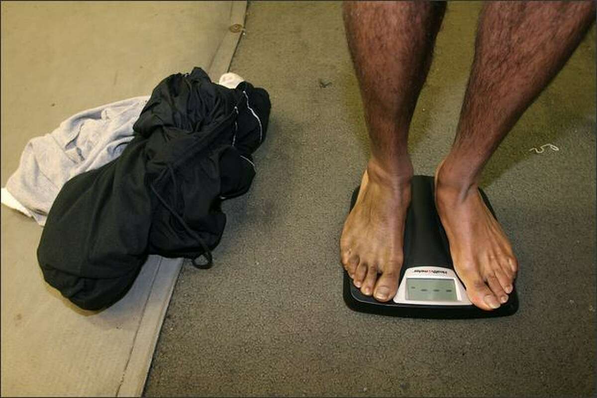 After dropping all his clothes, boxer Eddie Hunter weighs in on an electronic scale to see if he made his weight class during training at Bumblebee Boxing Club.