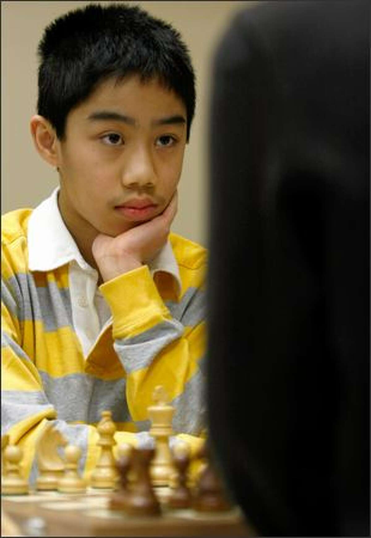 National master Michael Lee studies opponent Nat Koons Sunday at the opening of their eighth-round match in the Washington State Chess Championship in Seattle. At 14, Lee, of Bellevue, is rated in the top 1 percent of chess players in the nation.