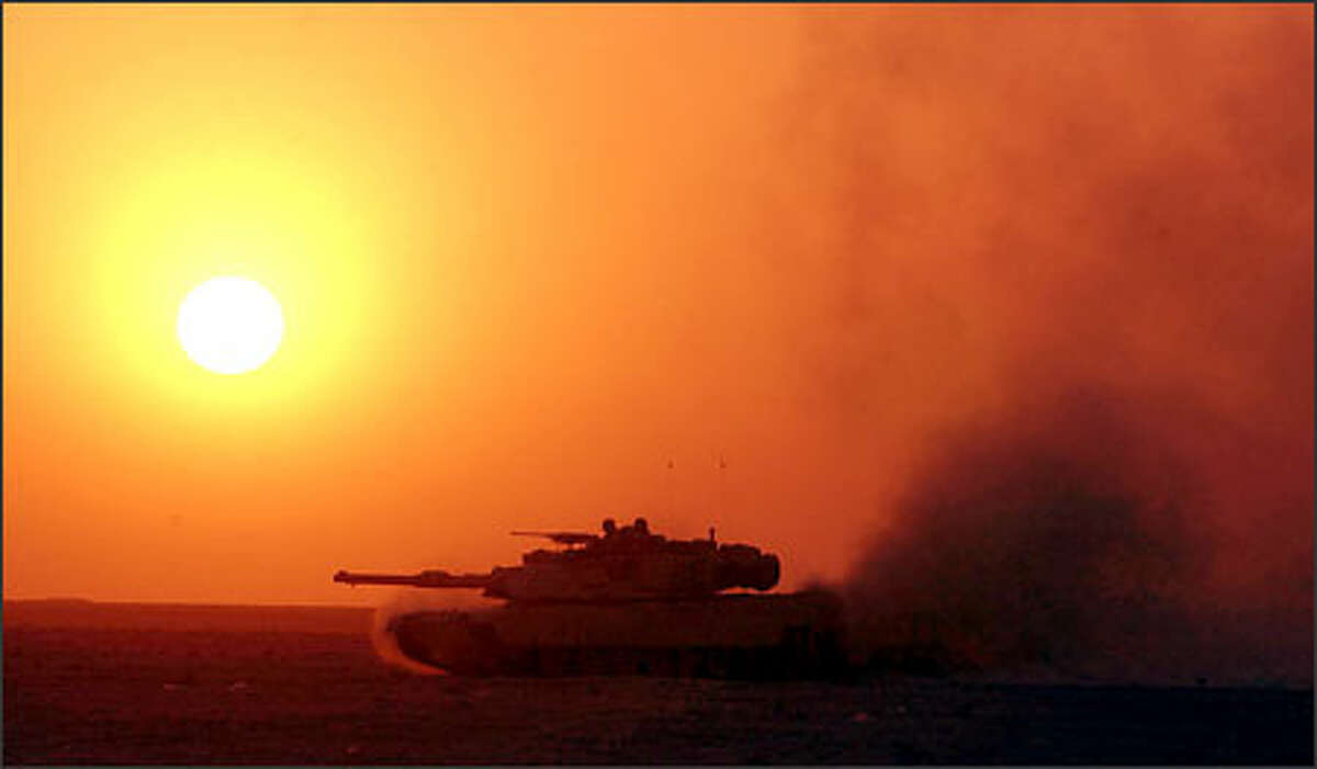 An Abrams tank races through the Iraqi desert as the sun sets yesterday, the 10th day of the war. President Bush has warned of "further sacrifice" ahead in the face of unexpectedly fierce fighting.