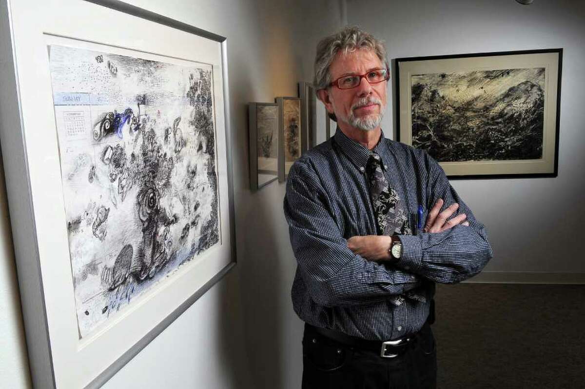 Artist Charles Steckler stands next to "Hanukkah Begins at Sundown," a mixed media drawing on a calendar page, part of an exhibit of his work at the Arts Center of the Capital Region, on Tuesday March 15, 2011 in Troy, NY. Behind him at right is his work, "Imaginary Alpine Landscape in a Storm." ( Philip Kamrass / Times Union )