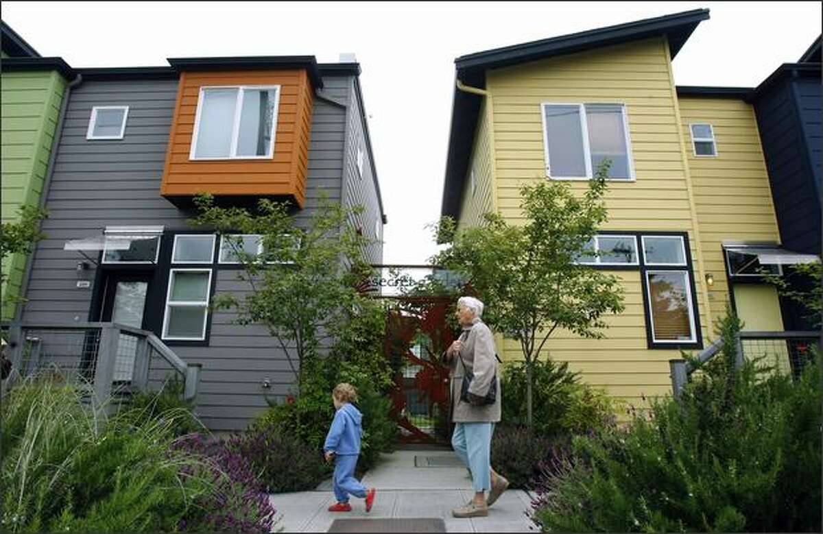 Erna Kooistra, visiting from Iowa, walks Monday with great-grandson Jonah Hieb past the Secret Garden townhouses on 11th Avenue East in Capitol Hill. The development got permission to deviate from 11 Seattle rules, including the amount of private open space and building lot coverage, depth and setbacks from property lines. The deviations allowed for a large, shared courtyard in the middle of the complex.