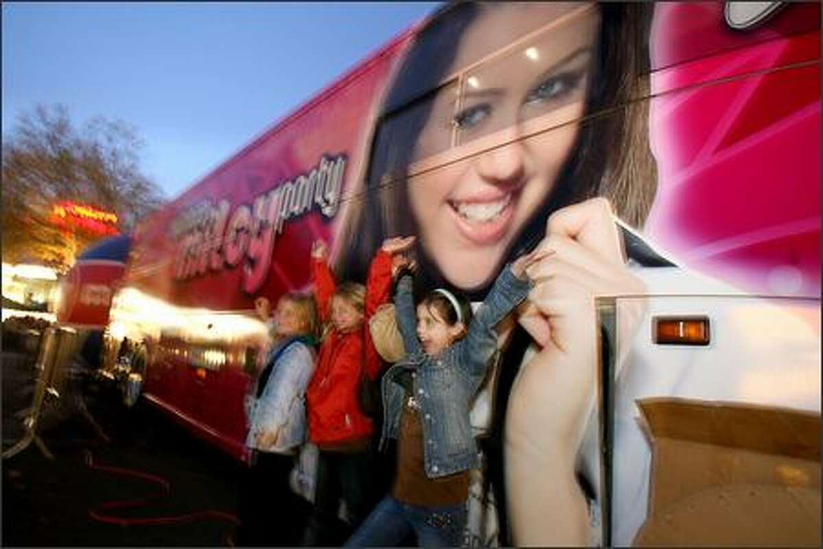Kelsy Byus, of Spokane flashes a smile next to the the Miley Cyrus aka Hannah Montana bus just before the concert at Key Arena in Seattle.