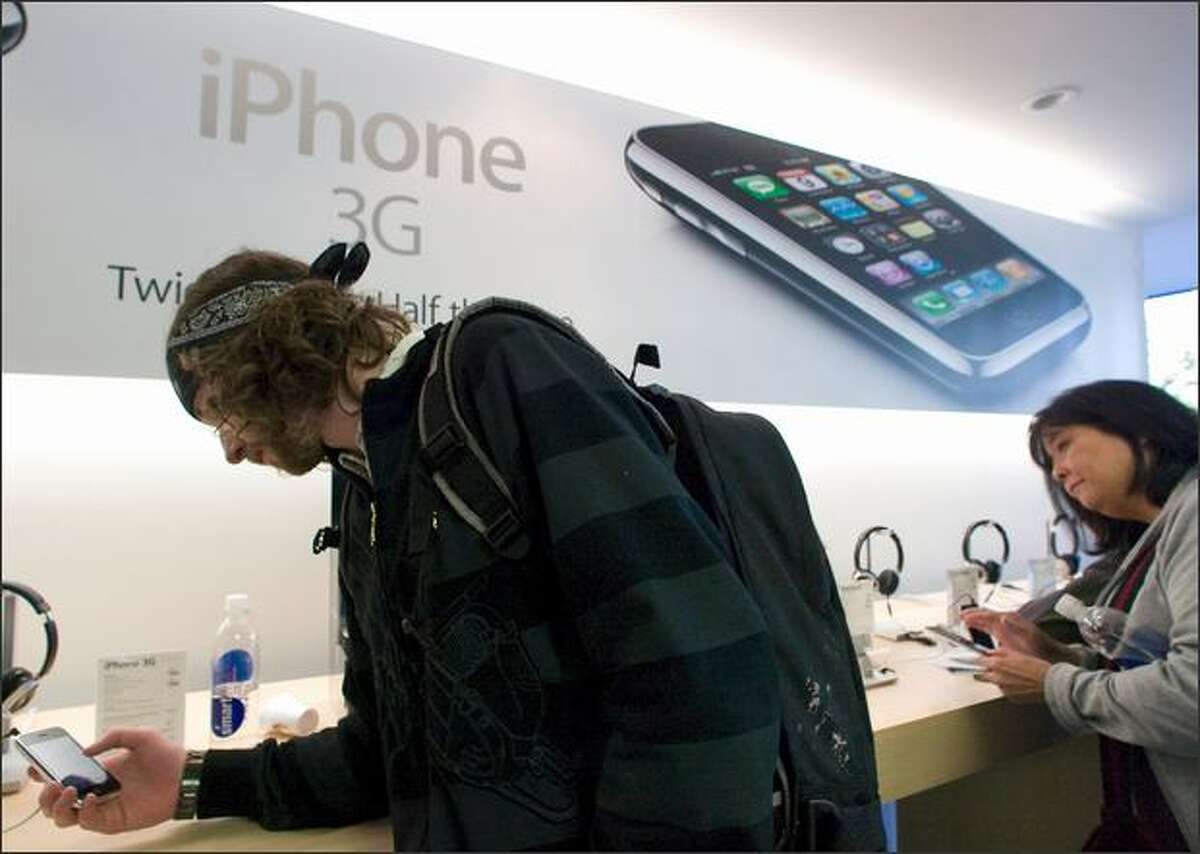 Isaac Prince, who had been in line since 3 a.m., uses an iPhone 3G at the University Village Apple Store on Friday. AT&T officials said the server problems were global.