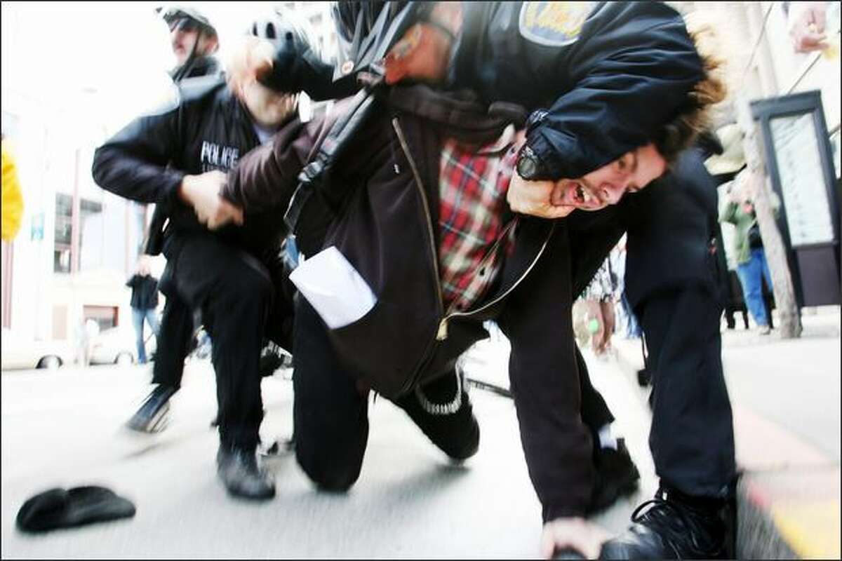 Seattle Police officers wrestle an anti-war protester to the ground during a protest to mark the four-year anniversary of the Iraq war.Eklund: Sometimes stupid luck can turn out all right. It happened in this photo when I had come from another assignment and was shooting at an ISO that was too low and an aperture that was too high, which resulted in a slow shutter speed. The camera was set at 250 ISO and the exposure was 1/25 of a second at f/7.0. Way too slow to be shooting news, but this happened within minutes of arriving at the protest march. Fortunately the focus was right on and I was moving with the subject, and I think the police had his head in a hammerlock, so there actually wasn't any movement there, and I think the motion by the police helps the photograph.