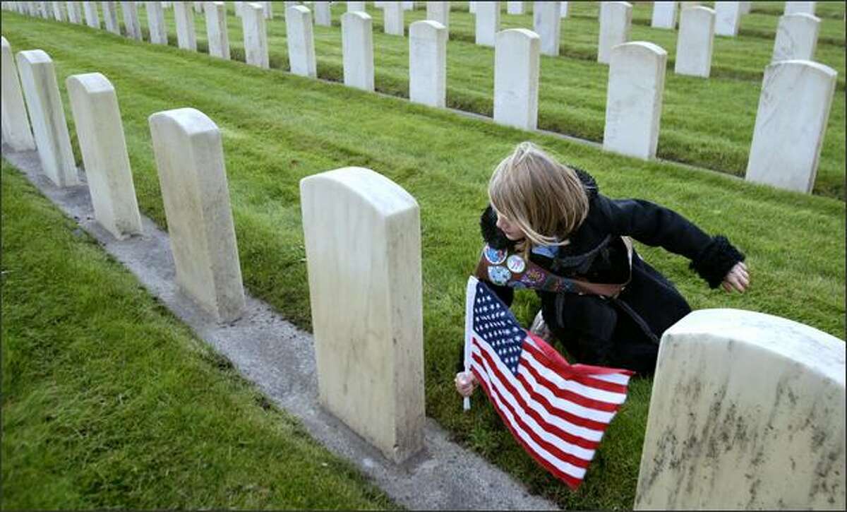Maddie Powers, 9, a Brownie with Troop 2238 in Mountlake Terrace, plants a flag at one of more than 5,000 gravestones at Veterans' Memorial Cemetery, adjacent to Evergreen-Washelli Cemetery in Seattle. Powers and other Girl Scouts visited the cemetery after taking part in its 58th annual Veterans Day Service of Remembrance.Rogers: I shot a full Veterans Day service at this cemetery, but thought I'd follow these scouts around afterward to get an extra picture or two for a photo gallery. I think this flag was pretty much the last of about 50 that they placed throughout the markers. I was walking toward this girl in the classic coat and she toward me, when she began to slow down and lean. I swooped in shooting and watched between frames as the wind on the flag, her sash, and her graceful arm all moved together into line with the flow of grave markers in my frame.