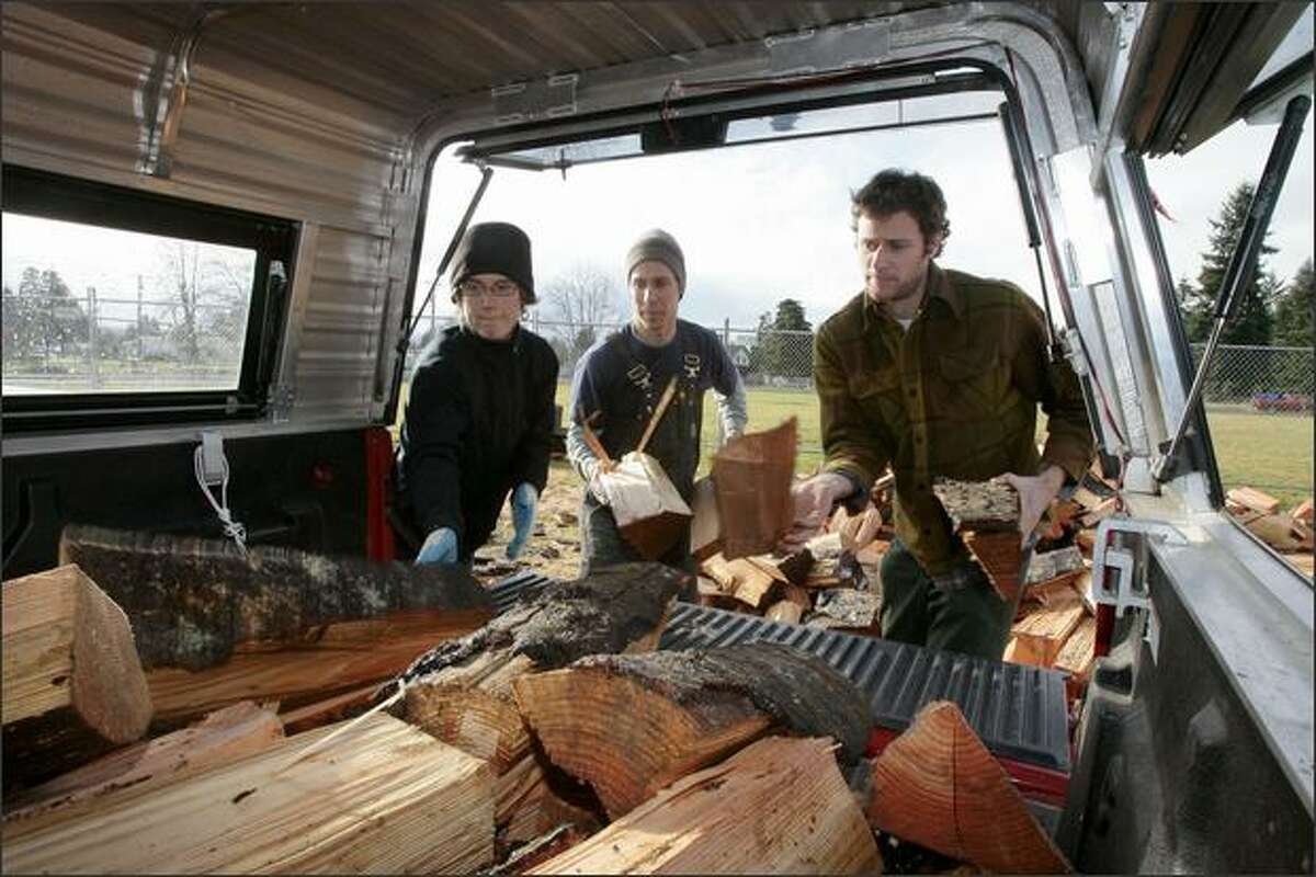 Joe Gabiou (center), owner of the Wobbly Cart Farm, gets help loading free firewood into the back of a truck from his friends Lindsey LaRock, left, of Seattle and Ryan White of Portland in Rochester. Gabiou's farm, located in the Independence Valley, was damaged during last week's flood.