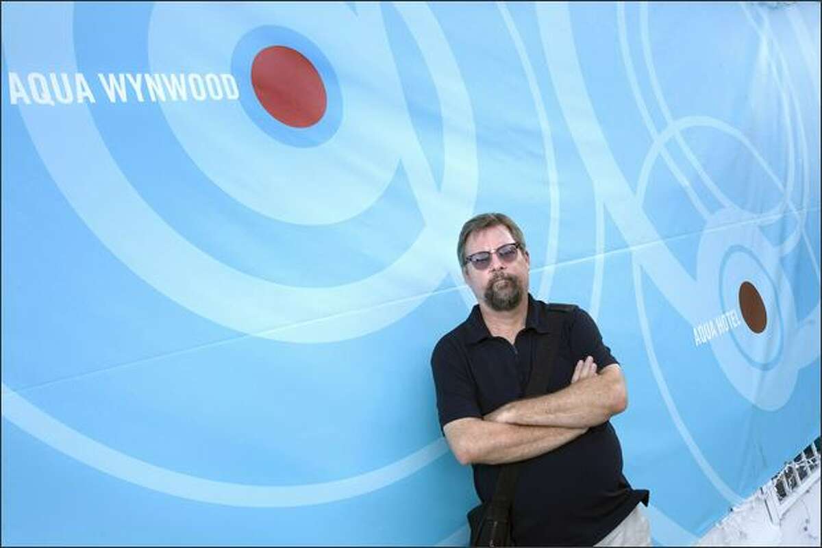 Dirk Park, one of the organizers of the Aqua exhibitions, poses in front of a sign for Aqua Wynwood and Aqua Hotel exhibition spaces at the Aqua Wynwood location in Miami Beach on Dec. 7. (Jacek Gancarz photo)