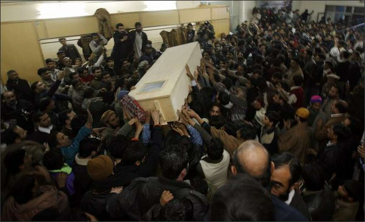 The body of former Prime Minister Benazir Bhutto is carried out of Rawalpindi General Hospital on Thursday in Rawalpindi, Pakistan. The opposition leader has died from a bullet wound to the neck after speaking at a rally in the northern city where an estimated 15 people were left dead by the explosion, a party official and Bhutto's husband have been quoted as saying.