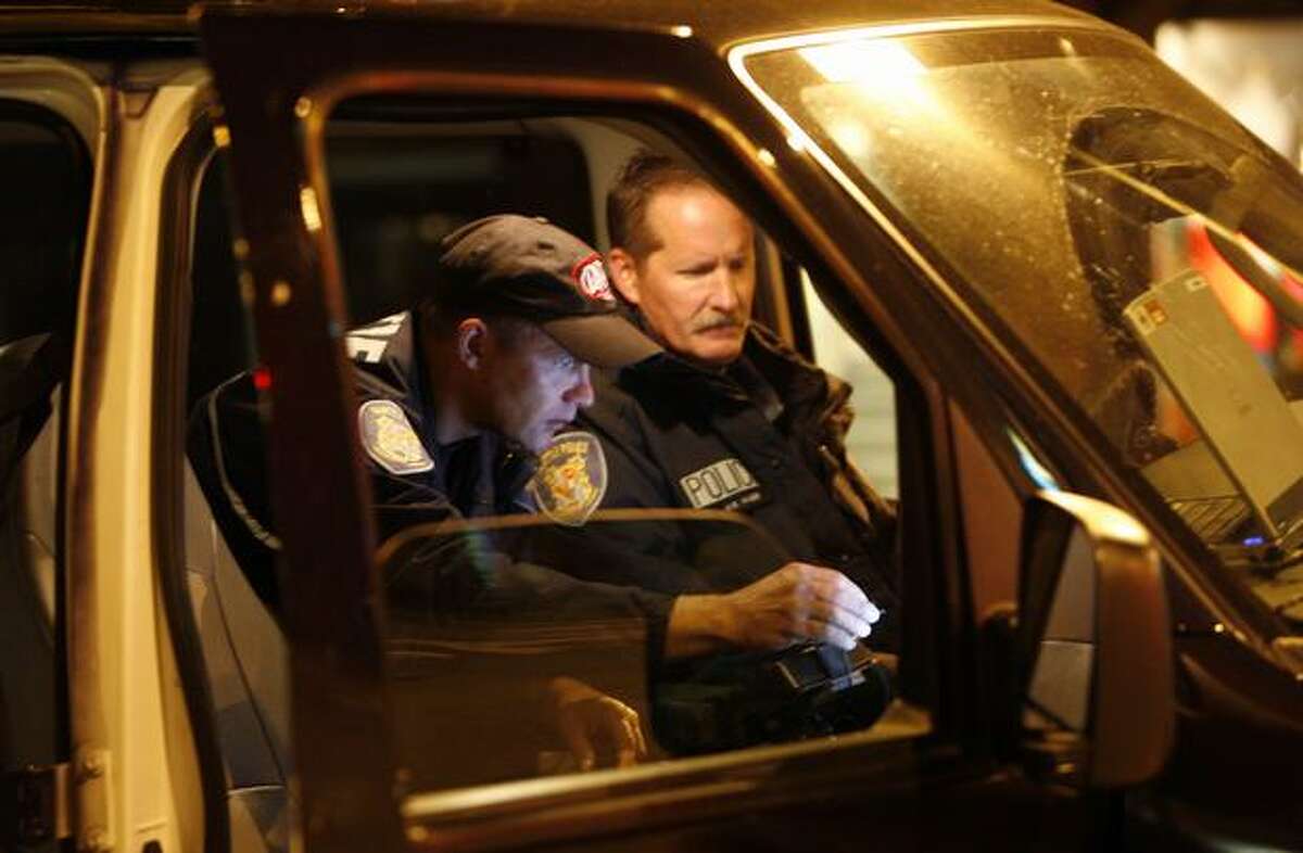 Seattle police officers and Neighborhood Corrections Initiative crew members Randy Jokela, left, and Vic Maes run a suspects name about 4:30 a.m. in Belltown.