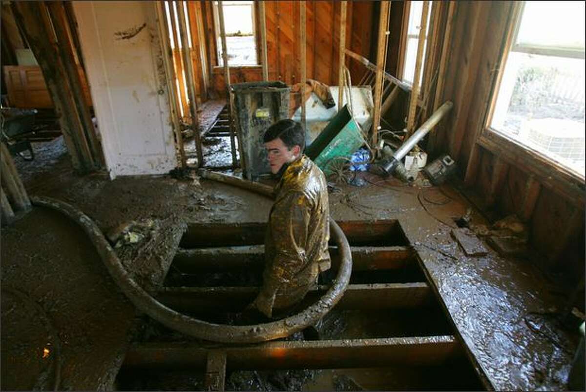 Dwight Martin, 22, a Mennonite volunteer from Rochester, Wash., stands in the mud-laden crawl space of Lewis County resident Steve Roberts' home in Curtis, Wash. He and four other young Mennonite men are helping Roberts, and other Lewis County residents, clean up and dry out after major flooding last December.