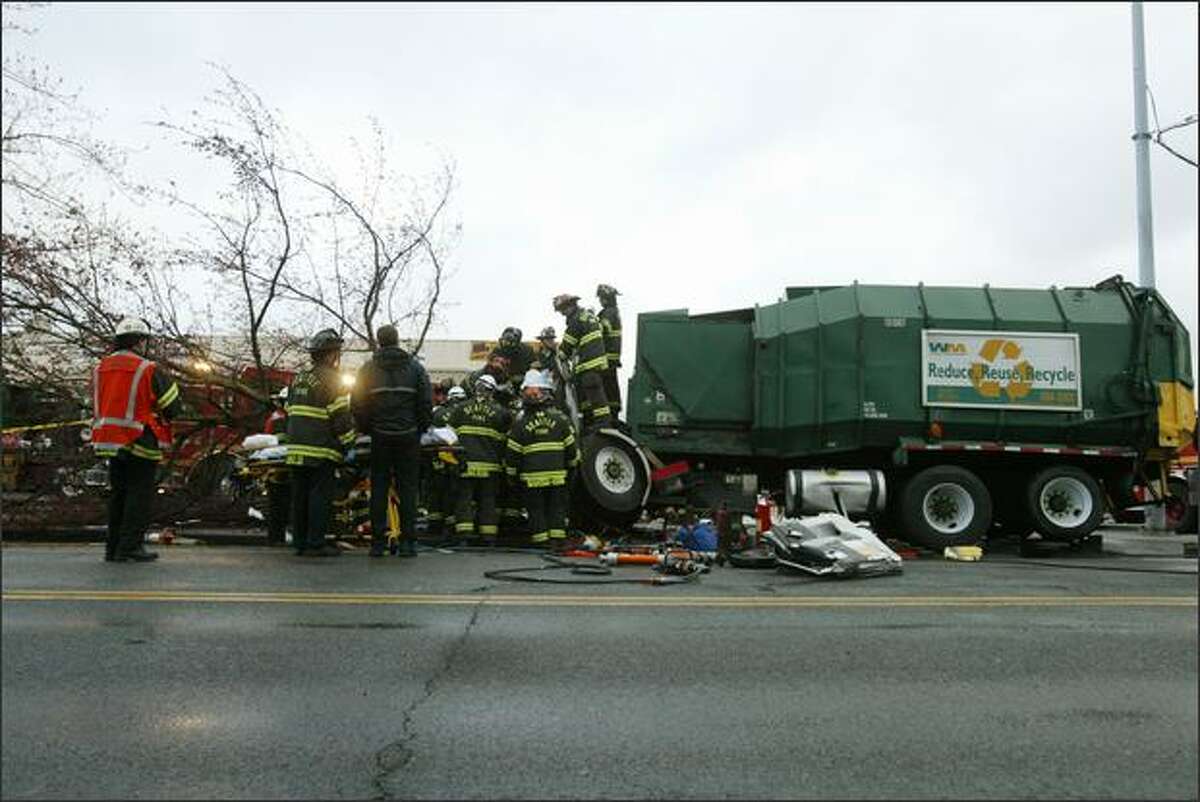 Seattle firefighters work to remove the driver from the wreckage of a garbage truck after he crashed into a tree early Wednesday on North 85th Street, at Palatine Avenue North. The extrication took about 90 minutes because the driver's legs were tangled with the steering column, dash and seat. According to Battalion Chief James Hilliard, the driver was transported to Harborview Medical Center in stable condition with lower leg injuries.