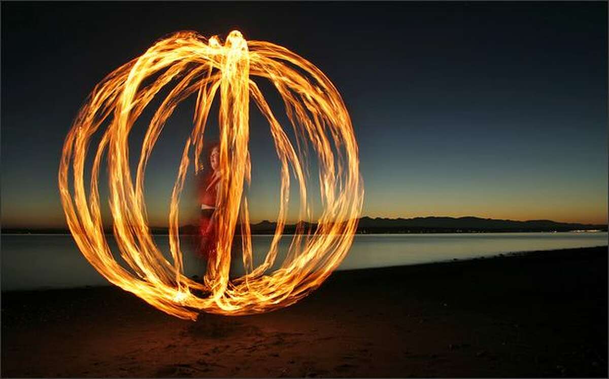In this 10-second exposure, Sarah Johnson of Seattle spins a cage-like ball of fire as she practices her art at Richmond Beach in Shoreline near Seattle. "Fire has always been a fascination for me," Johnson recalled. "I was that kid at the campfire lighting twigs ... and watching them burn."