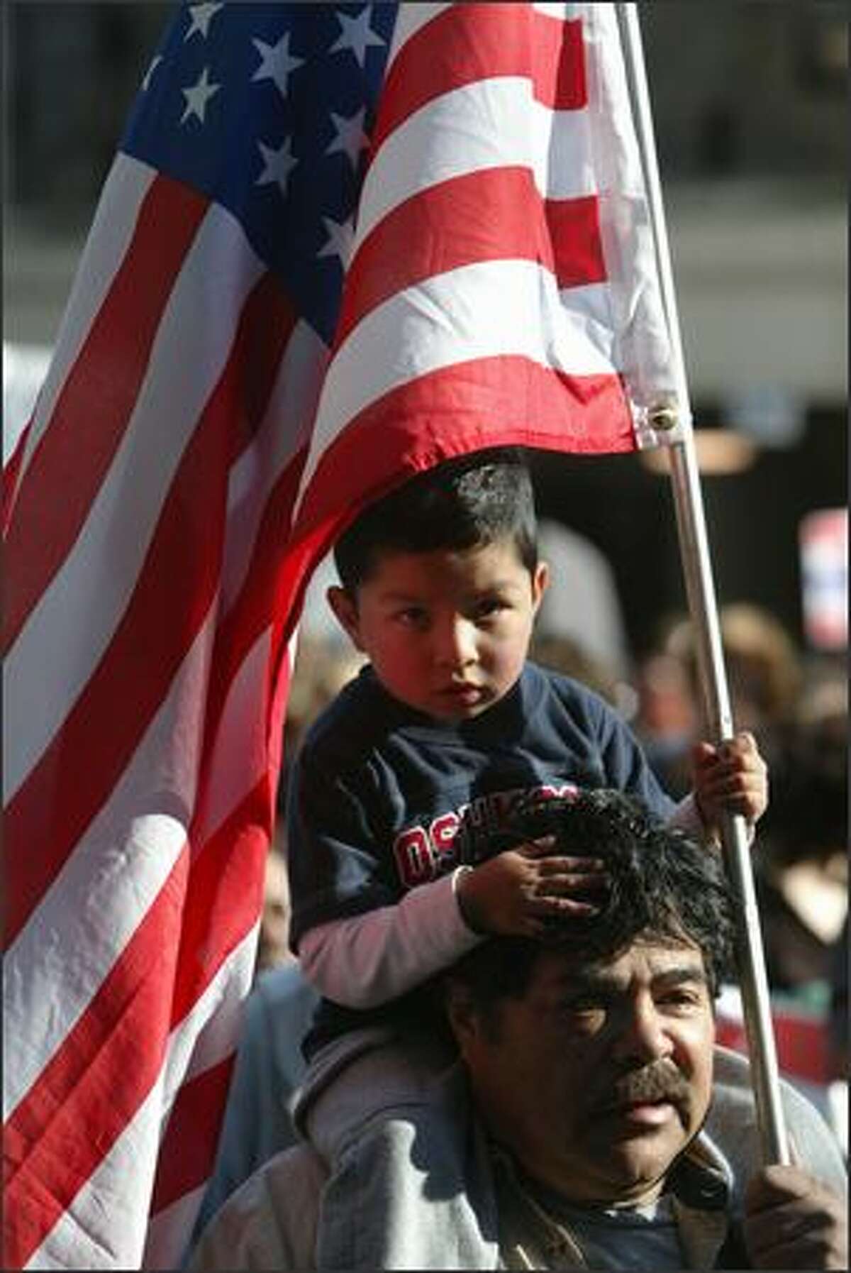 Daniel Cruz 4 holds an American flag sits on his grandpa's, Enrique Lopez, shoulders as they participate in the annual May Day March in downtown Seattle.