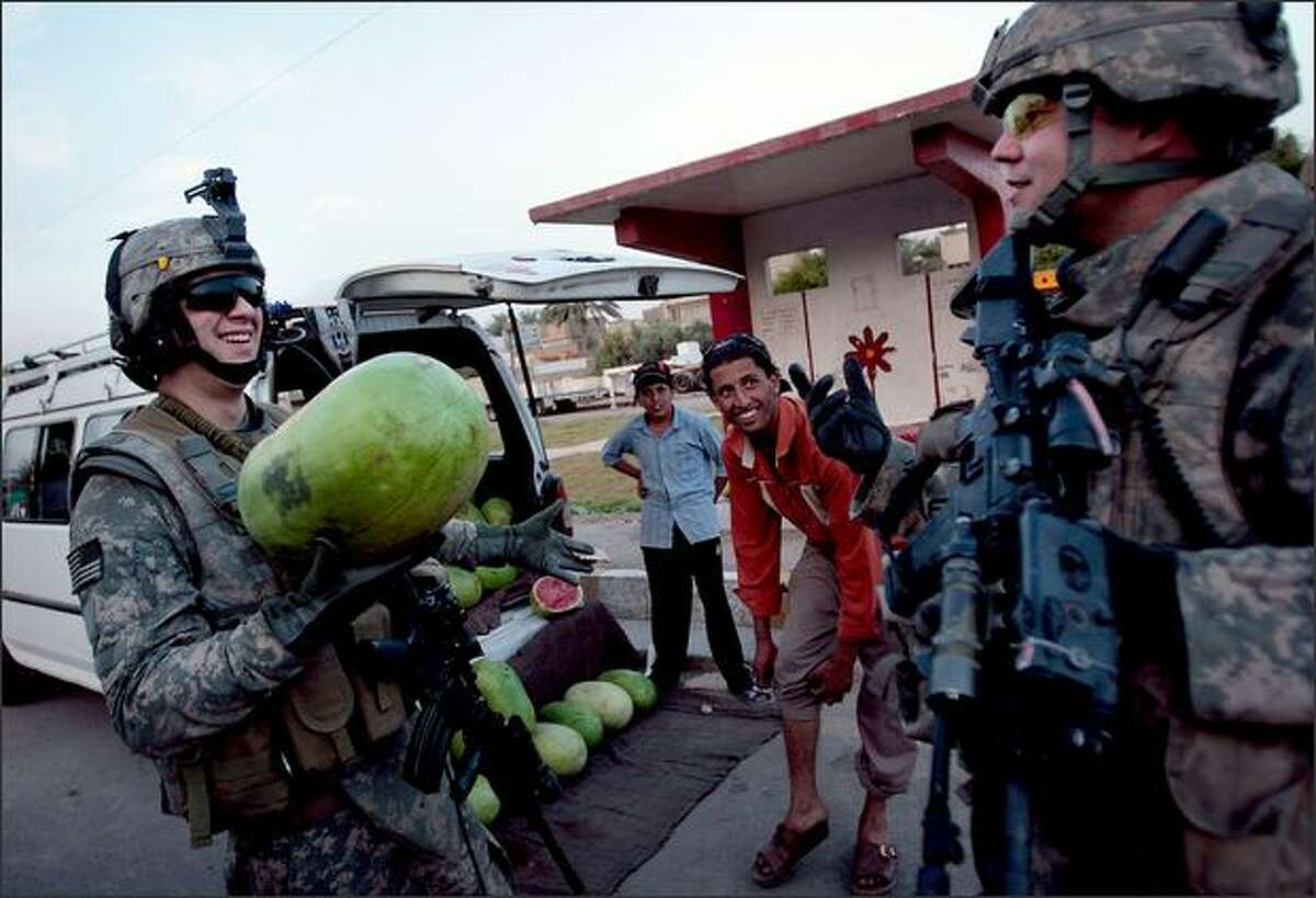 Cpl. Daniel Hirsch of Liberty, New York, left, asks Staff Sgt. Robert Thomas of New Burgh, Indiana, right, what to do with the watermelon he had just bought from a bemused street vendor in east Baghdad, Iraq. Both soldiers are in the 3-89 Cavalry Regiment of the 10th Mountain Division.