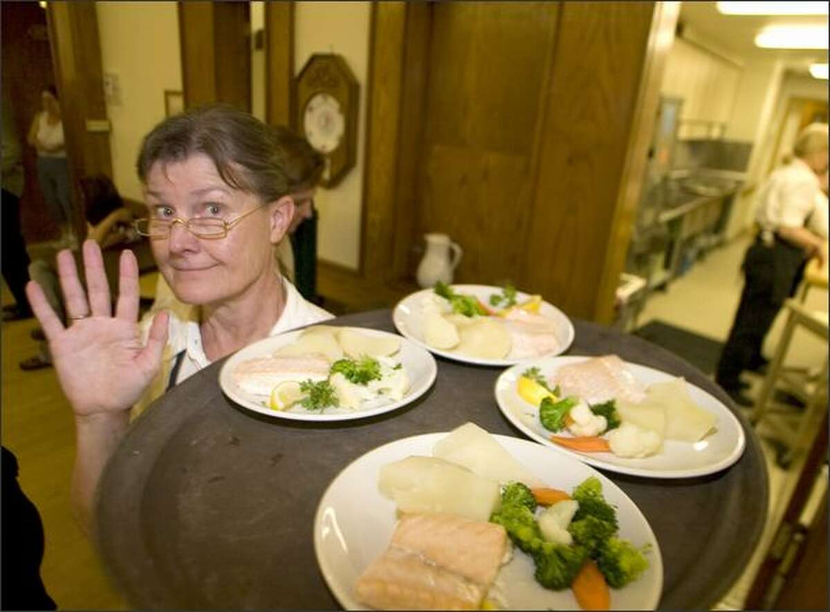 Banquet server Angelia Amundson rushes by with a tray of baked salmon, steamed potatoes and veggies while working at the Norwegian Constitution Day Luncheon at Lief Erikson Hall in Ballard.