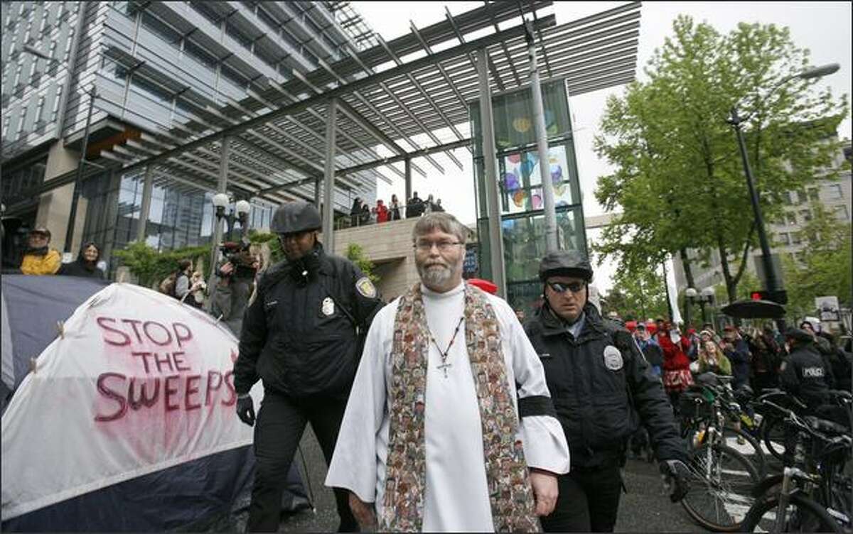 Seattle police officers arrest Rev. Rich Lang of Trinity United Methodist Church, during a protest regarding the treatment of the homeless at Seattle City Hall.