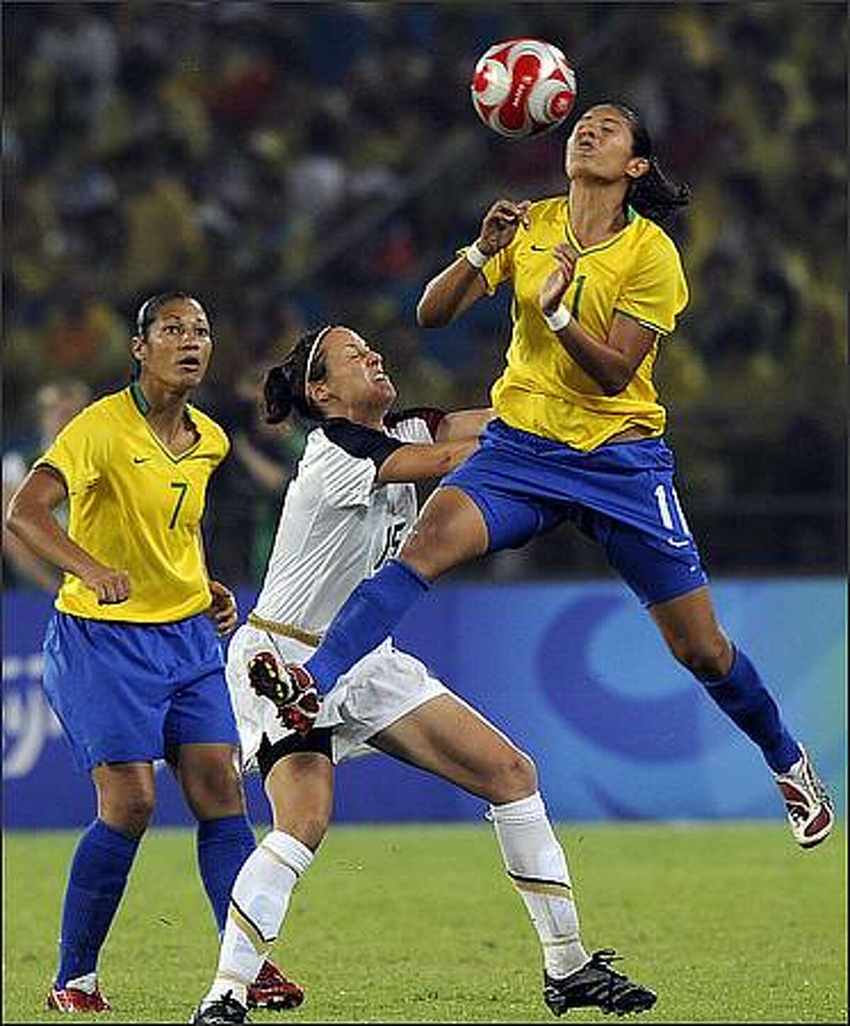 Brazil's Cristiane (R) vies for the ball with Kate Markgraf (C) of US while Brazil's Daniela looks on during the 2008 Beijing Olympic Games women's football Gold medal match at the Workers Stadium in Beijing.
