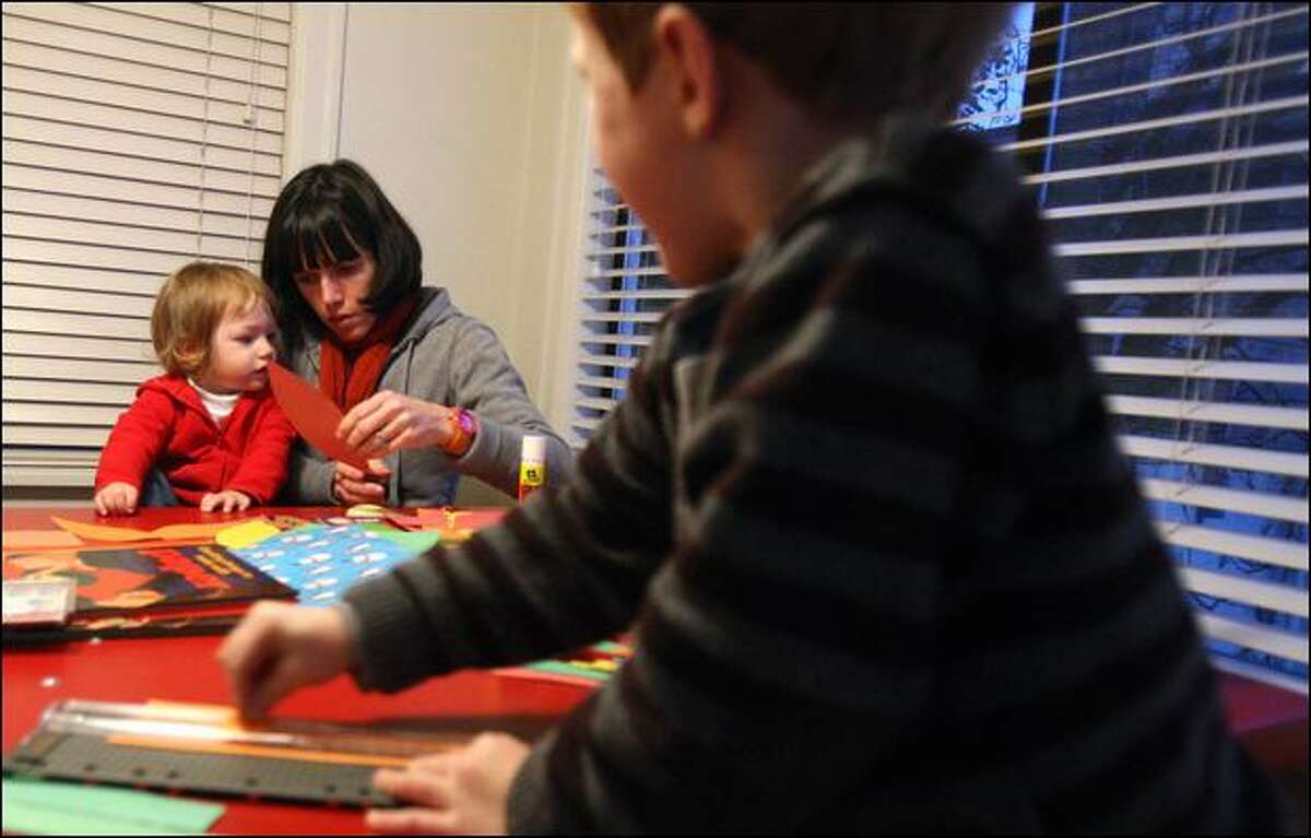 Cambria Cox makes a decorative holiday turkey with construction paper with her daughter Vivian Murphy, 1, and son Hayden Murphy, 4, at their South Seattle home. In an effort to save money on the holidays, Cox's family is making a lot of Its own seasonal cards and decorations.