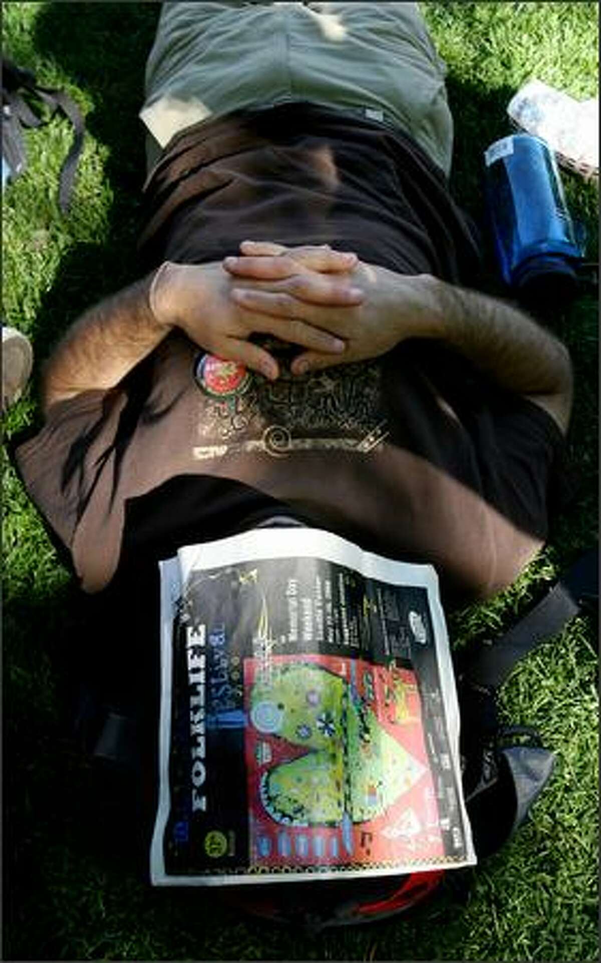 A music fan takes a rest with the help of a Northwest Folklife Festival program.