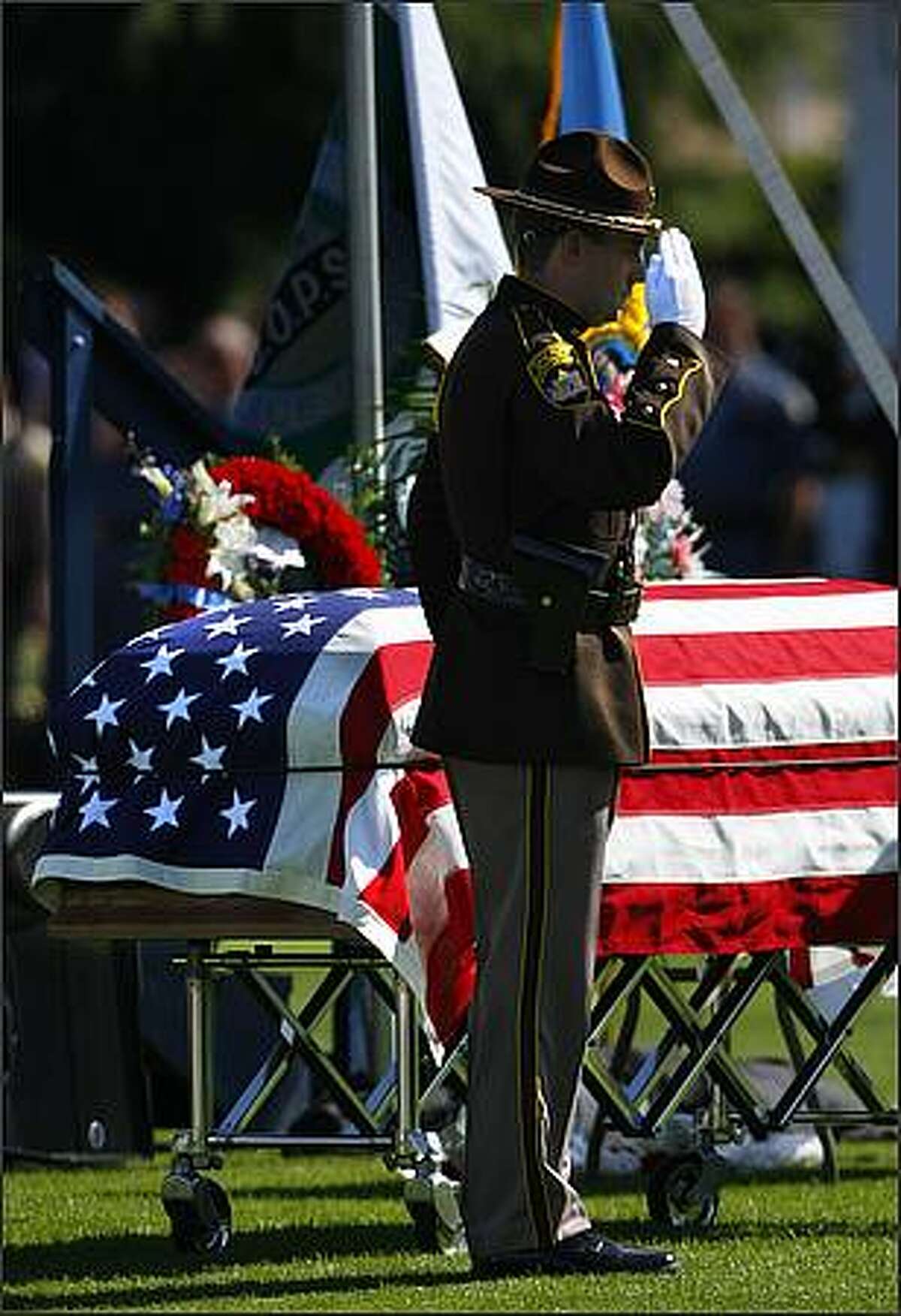 A Skagit County Sheriff Office representative salutes the coffin of Deputy Anne Jackson.