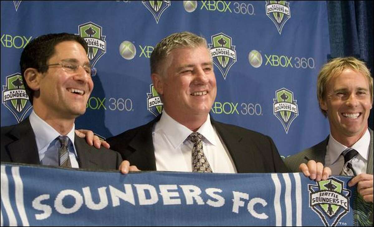 Sounders FC general manager Adrian Hanauer, left, and technical director Chris Henderson, right, pose with new coach Sigi Schmid and a team scarf Tuesday.