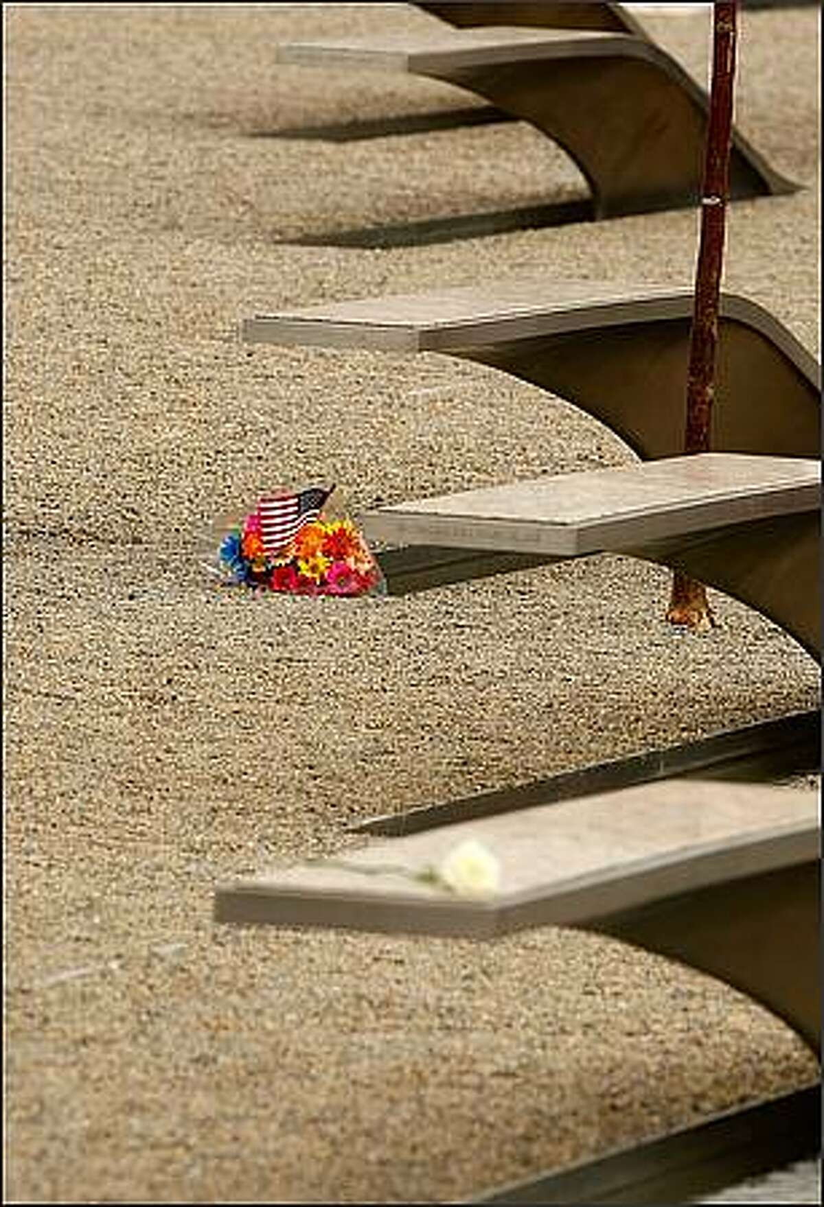 Family members leave flowers on the "memorial units" at the Pentagon Memorial after the dedication of the Pentagon Memorial September 11, 2008 in Arlington, Virginia. U.S. President George W. Bush will dedicate the memorial, made up of 184 "memorial units" each dedicated to an individual victim killed at the Pentagon when American Airlines Flight 77 slammed into the Department of Defense's headquarters on September 11, 2001. (Photo by Chip Somodevilla/Getty Images)