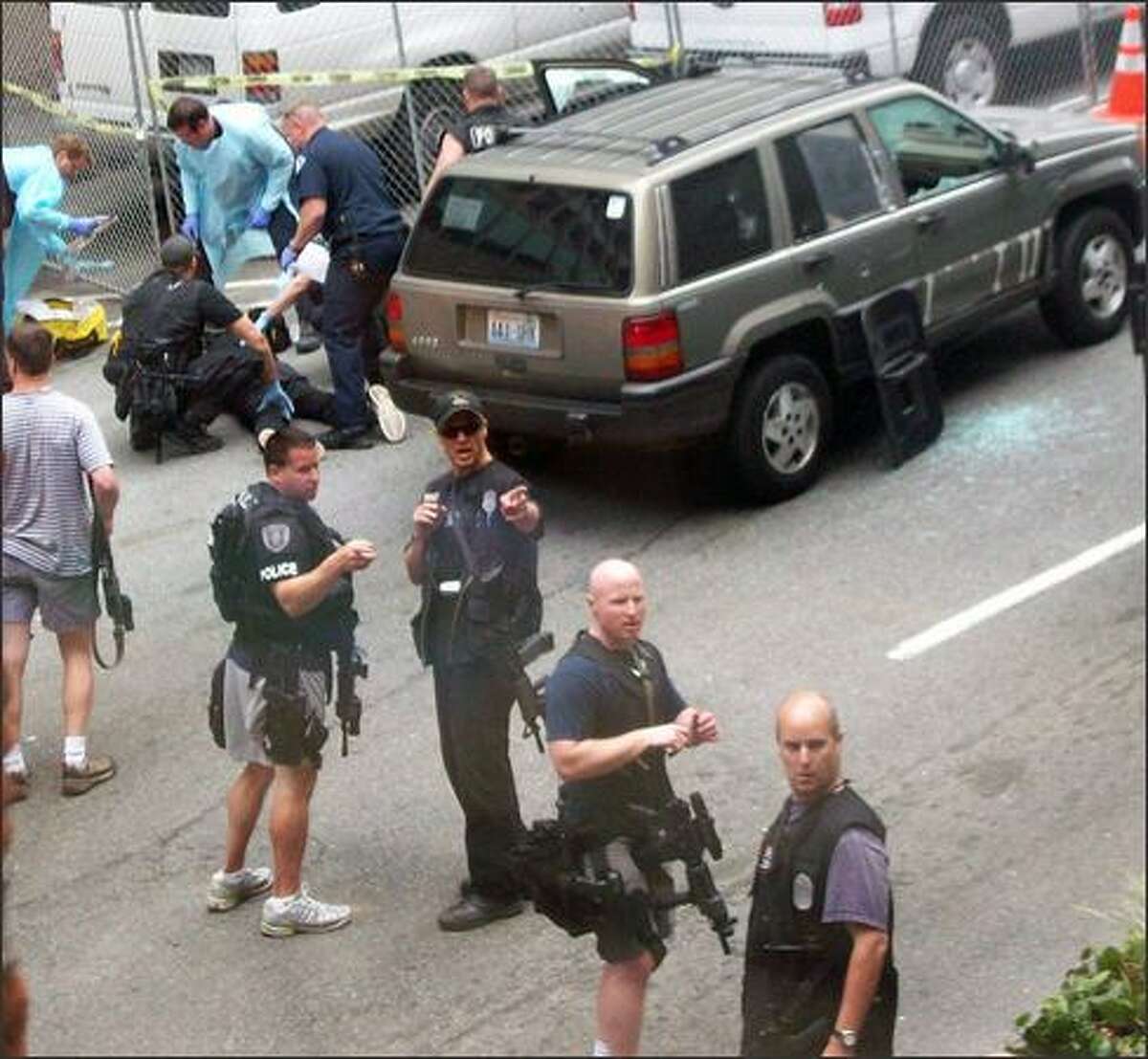 Paramedics attend to a subject (back left) who was shot by police and pulled from the Jeep shown. (Photo by Michele DeMaris)
