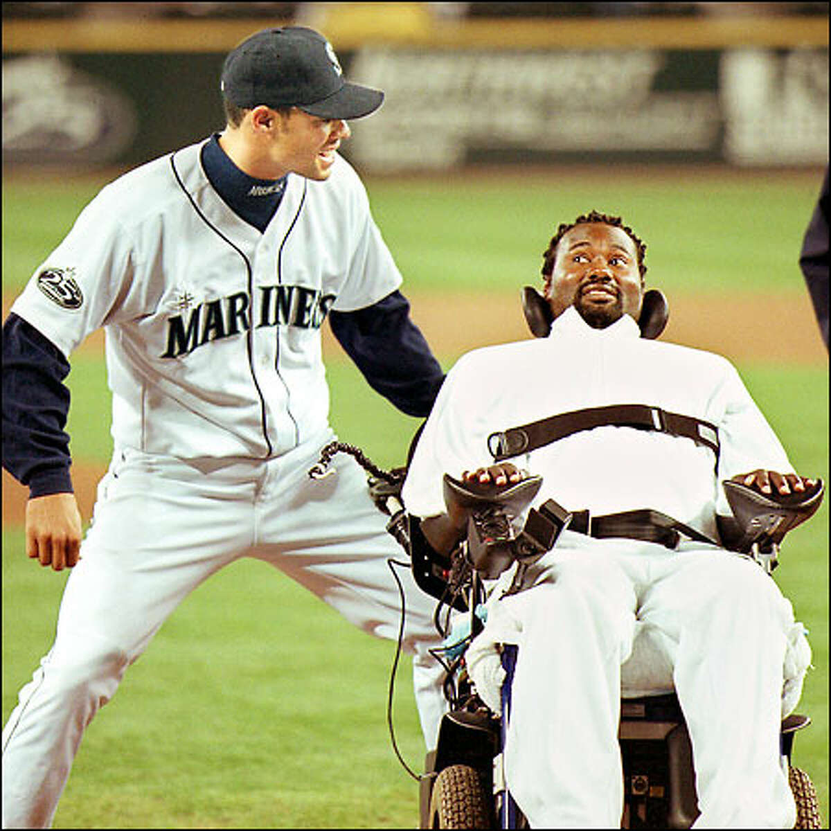 Former University of Washington football player Curtis Williams jokes with Mariner Charles Gipson before a game at Safeco Field on April 24. Williams, who threw out the first pitch prior to the game against Anaheim, became paralyzed after being injured during a game at Stanford on Oct. 28, 2000. Williams died in Clovis, Calif., on May 6.