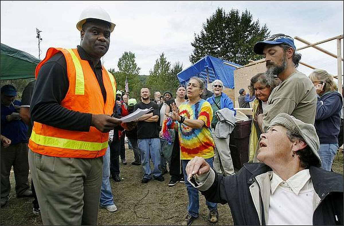 Residents of "Nickelsville" have questions for Alex Wiggins, acting chief for Seattle Department of Transportation, after Wiggins made the initial order for people to clear the homeless encampment in West Seattle on Friday.