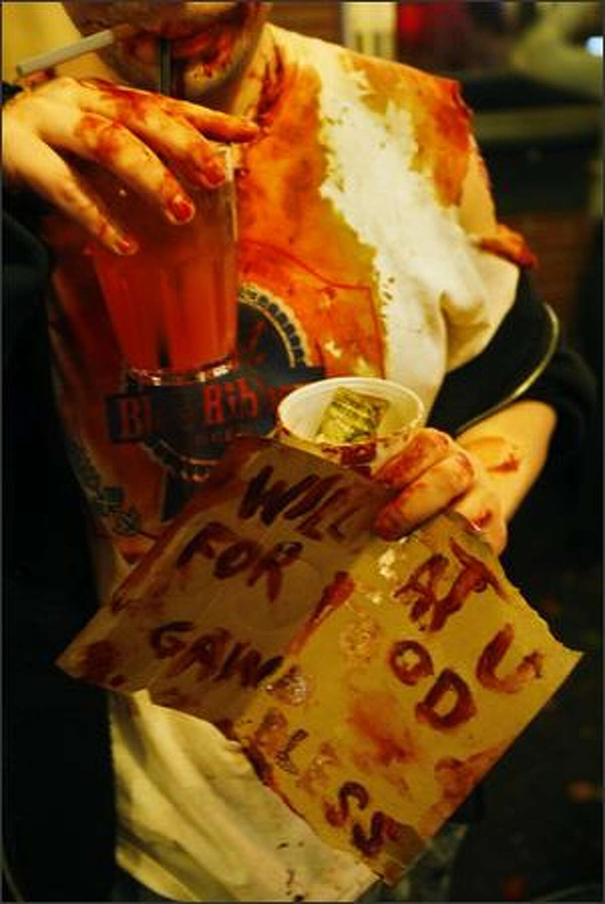 A "zombie" holds a sign that says "will eat u for food, gawd bless."